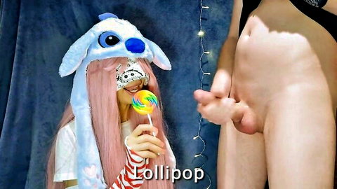 Pink-haired girl in Stitch cosplay hat holds lollipop near erect penis on thigh in taste-guessing tease
