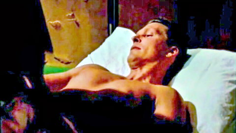 Shirtless fit man relaxing on bed in masseuse massage scene