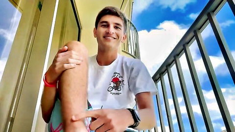 Tall skinny young guy smiling on balcony in casual white t-shirt, hot solo tease
