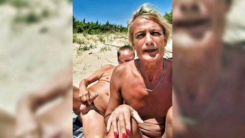 Blond trans woman and cis man nude on nudist beach, intimate outdoor embrace