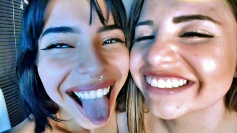 Two smiling women with intense eye contact, tongues out in ASMR tease