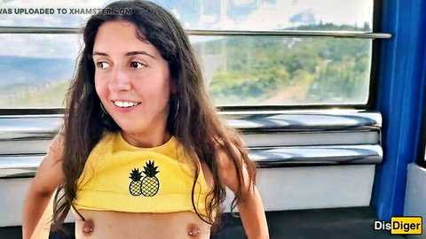 Brunette smiling in yellow pineapple top with nipple piercings on Ferris wheel