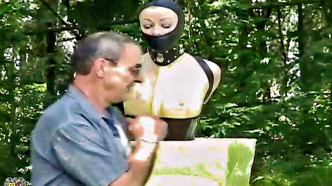 Man installs foam latex bondage mannequin in forest outdoor fetish scene