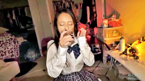 Cute Asian schoolgirl in plaid skirt and blouse holding drink seductively