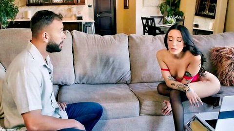 Tattooed brunette MILF with big tits exposes nipples in red bra, legs spread on couch with bearded man
