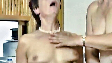 Mature Asian woman with pearl necklace, mouth open, grabbed by shirtless man
