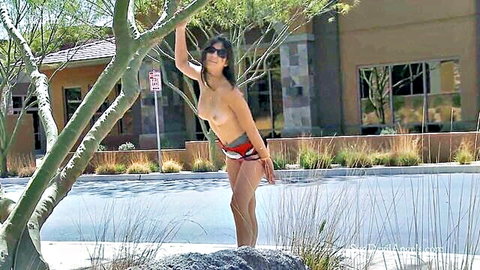 Topless Kristen poses shamelessly outdoors in red bikini bottoms on sunny street