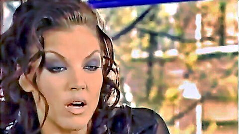 Seductive brunette with curly hair, smoky eyes, open mouth in black top