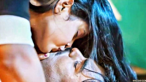 South Asian woman passionately kissing man's neck in intimate closeup embrace