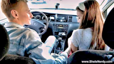 Nerdy redhead teen girl in glasses smiles flirtatiously at boyfriend driving car
