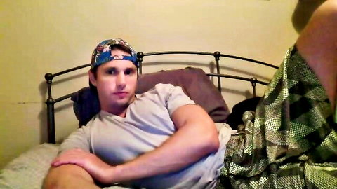 Muscular white guy in cap and shorts lounging on bed, amateur gay thumbnail