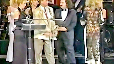 Chloe Nicole and Barbara Doll in glamorous stage outfits with men at podium