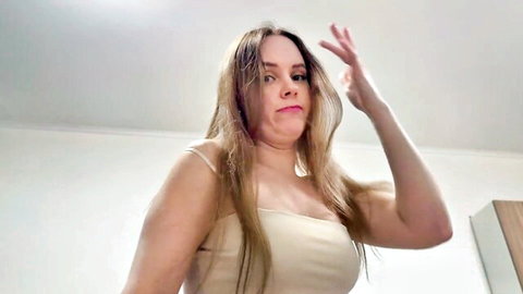 Blonde woman in sheer tank top teasing with peace sign gesture