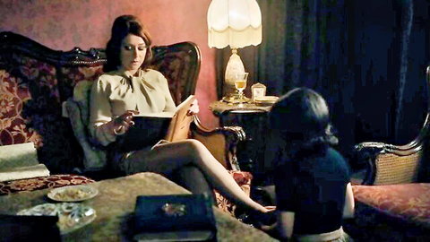 Vintage lesbian scene: redhead in blouse reads to brunette in dress, The Duke of Burgundy