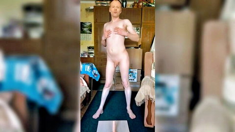 Skinny naked man stands legs spread over large white dildo in cluttered bedroom