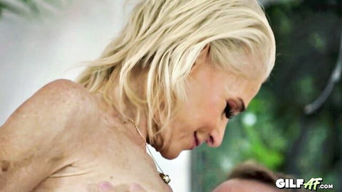 Smiling mature blonde GILF flaunts her saggy tits in outdoor profile view