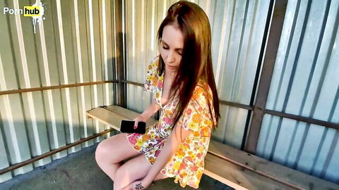 Young stepmom in floral dress sits upset, holding phone after quarrel