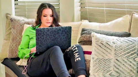 Asian brunette woman in green top and sweatpants working on laptop
