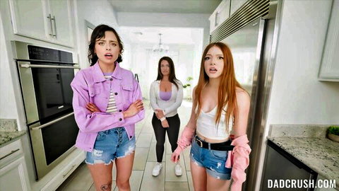 Shocked brunette teen in shorts arms crossed with redhead friend and stepmom in kitchen on DadCrush