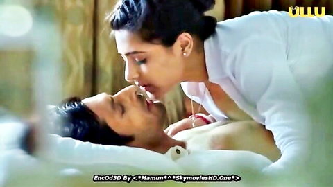 Indian woman passionately kisses shirtless man in bed, on top