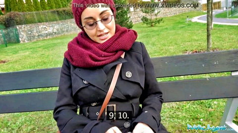 Yasmeena in hijab and coat sits on park bench for outdoor amateur debut