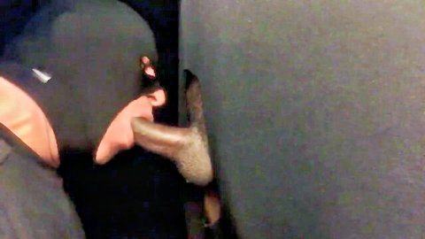 Masked performer orally milking dark-skinned cock through glory hole