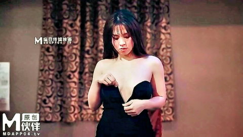 Busty Asian babe seductively pulls open black strapless dress exposing deep cleavage and huge tits