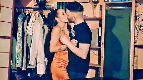 Busty brunette in sexy orange dress passionately kisses muscular man in taboo mother-son scene