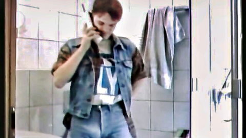 Redhead in denim jacket and jeans talks on phone in locker room