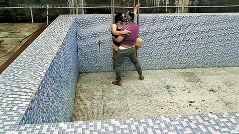 South Asian couple passionately fucking standing in empty pool, her bare tits pressed against him