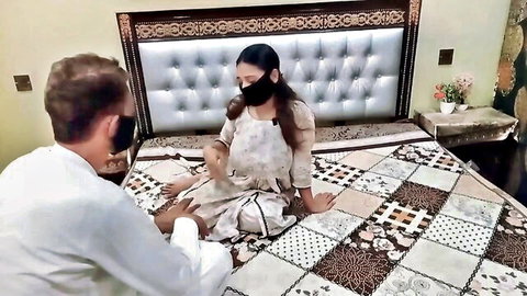 Masked curvy Indian wife in shalwar kameez sits intimately with masked man on bed teasing foreplay