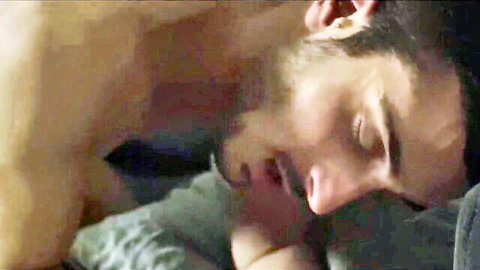 Bearded muscular hunk kissing sleeping man's neck passionately in bed