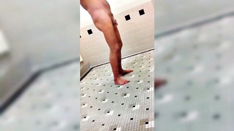 Skinny nude man standing in steamy tiled shower exposing bare legs and ass