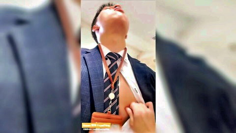 East Asian man in suit moans ecstatically with tie pulled during gay blowjob