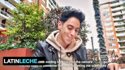 Handsome Latino guy in hoodie and leather jacket smiling at camera outdoors on LatinLeche