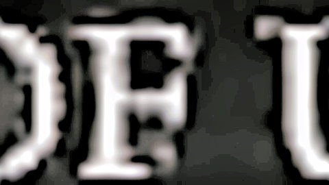 Blurry white DTU text logo on black background close-up
