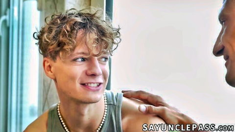 Smiling curly-haired young twink touched intimately on bare shoulder by muscular tanned mature daddy