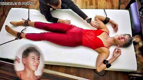 Bound smiling woman in red lace lingerie and tight pants groped by man in bondage scene