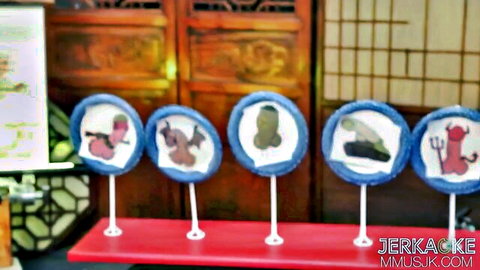 Row of colorful cartoon Shrek devil tank lollipops on sticks displayed on red table against wooden door
