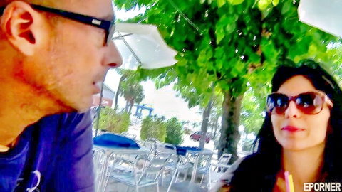 Sexy brunette bimbo in sunglasses flirts with man outdoors at cafe