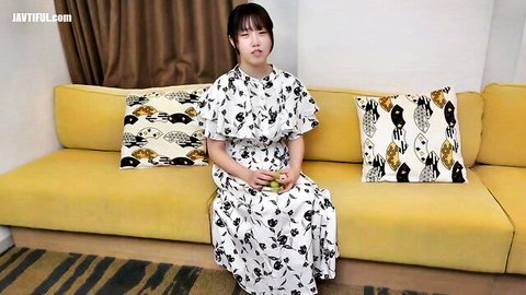 Slim Asian woman in white floral off-shoulder dress sitting demurely