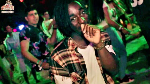 Black guy with dreads holds joint at wild crowded college party with girls in tight tops