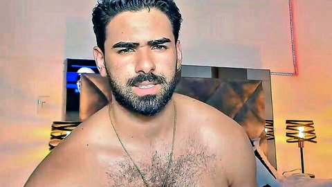 Handsome bearded Latino hunk shirtless flexing hairy chest on bedroom bed webcam