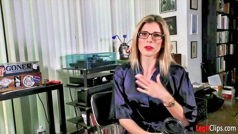 Blonde MILF with glasses in satin blouse gestures seductively in home office