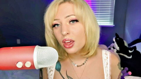 Blonde ASMR girlfriend teases with tongue out, deep cleavage in lacy top near mic