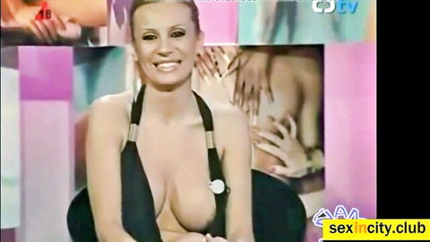 Smiling blonde flashing huge tits with deep cleavage on sex TV show