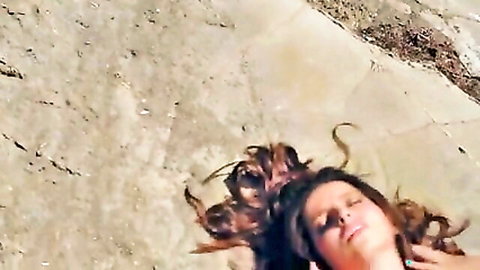 Topless brunette with big tits relaxing on sunny beach