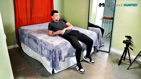 Beefcake Dmytro lounging muscular on bed in grey tee and sweats
