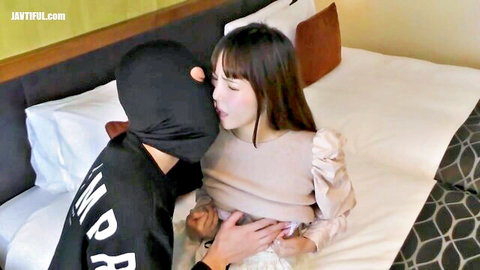 Masked half-white man kissing petite Asian woman in blouse and skirt