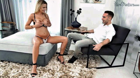 Blonde MILF squeezes her huge exposed tits in thong seducing smiling young man in chair